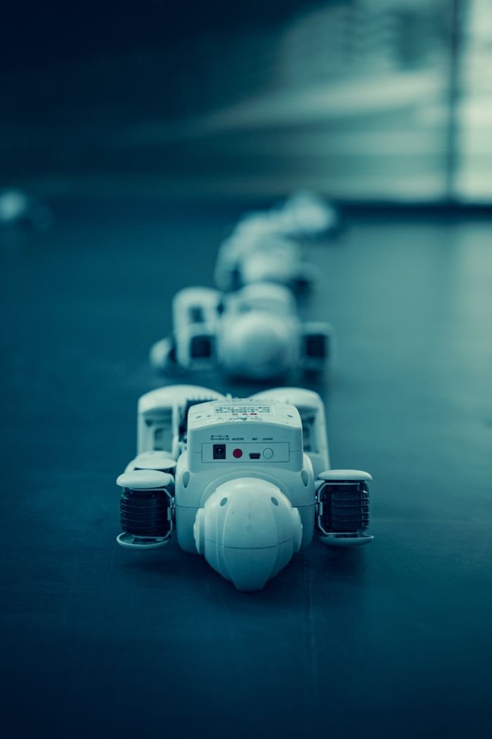 hero-img-02 Vertical shot of white robots aligned on a dark surface, emphasizing technology.