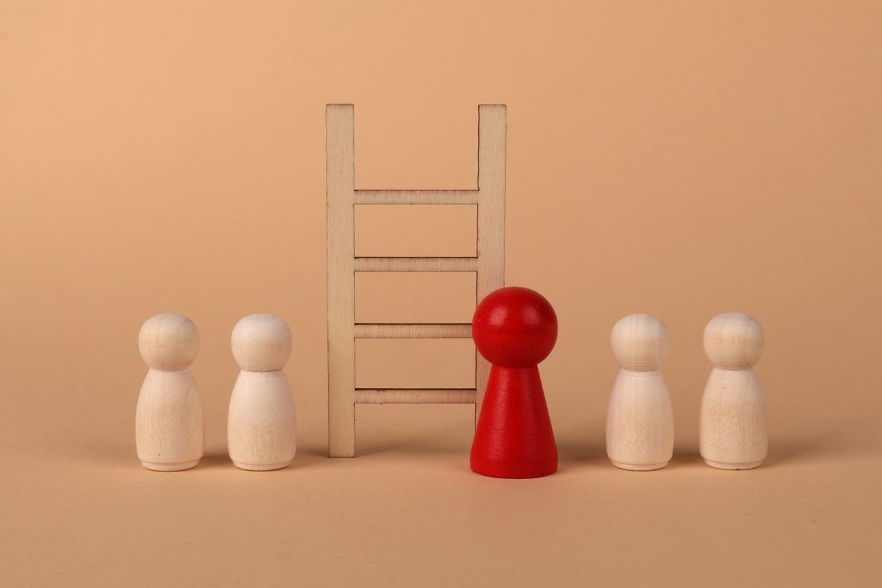 Abstract representation of leadership with wooden figures and ladder on a neutral background.